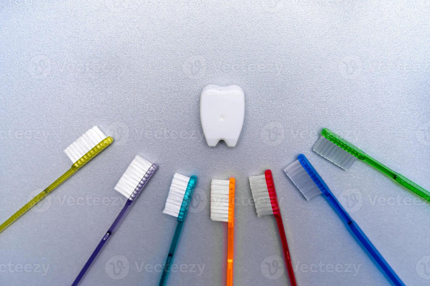 Colorful tooth brushes lay around tooth floss in tooth toy shape. photo