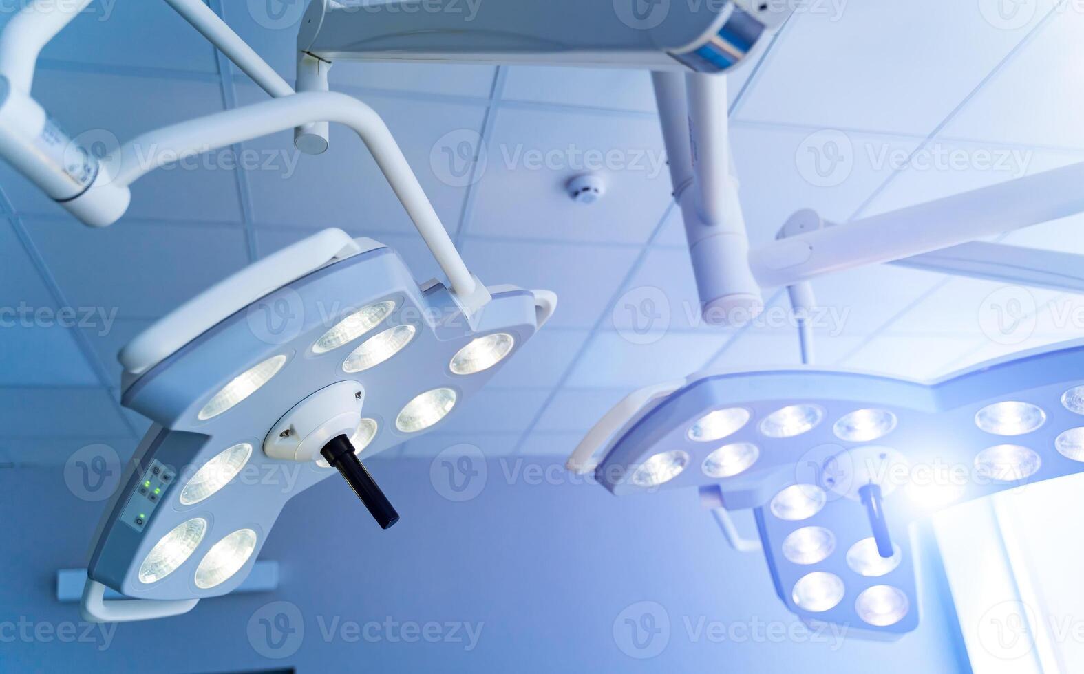 Two surgical lamps in operation room. Blue cast light in clinic. Modern equipment in surgery room. Operating theatre. Closeup. photo
