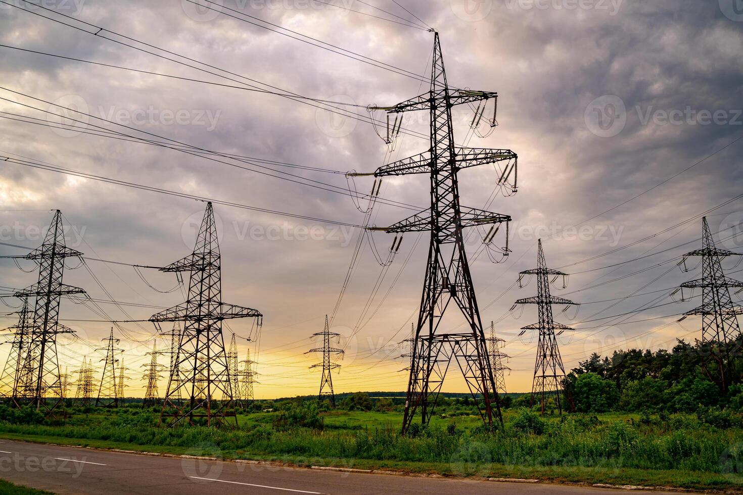 Electricity pylons and high-voltage power lines on the green grass. Power plant. Electrical power grid. View from below. photo