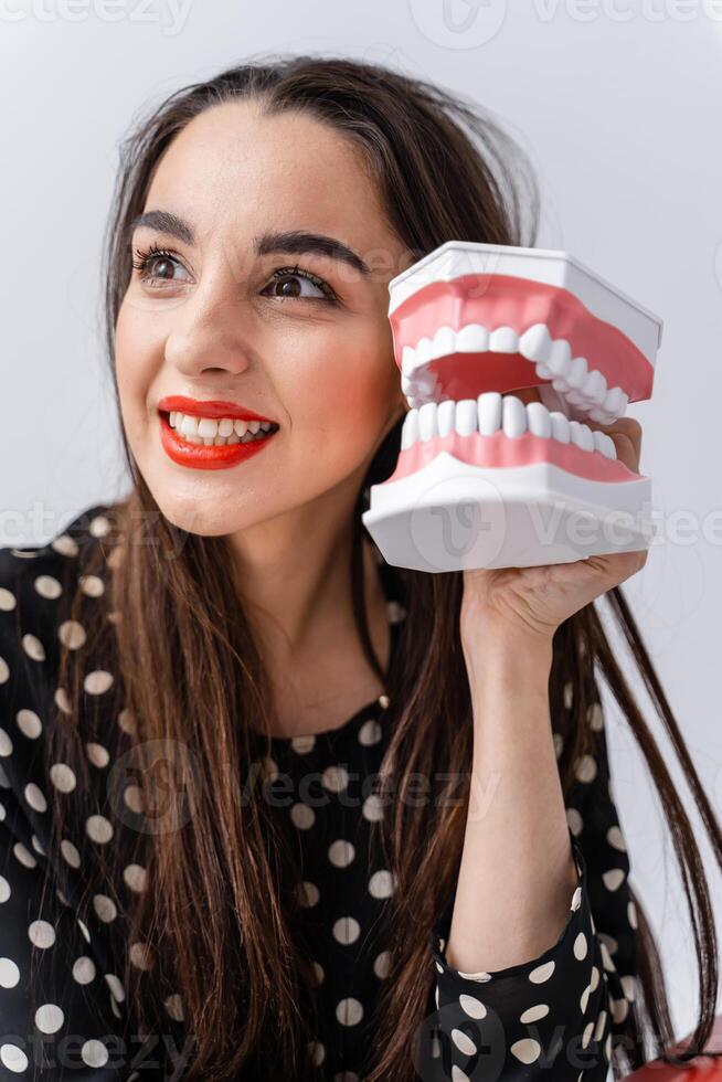 Woman holding educational model of oral cavity with teeth on white background. Funny emotions and expressions. photo