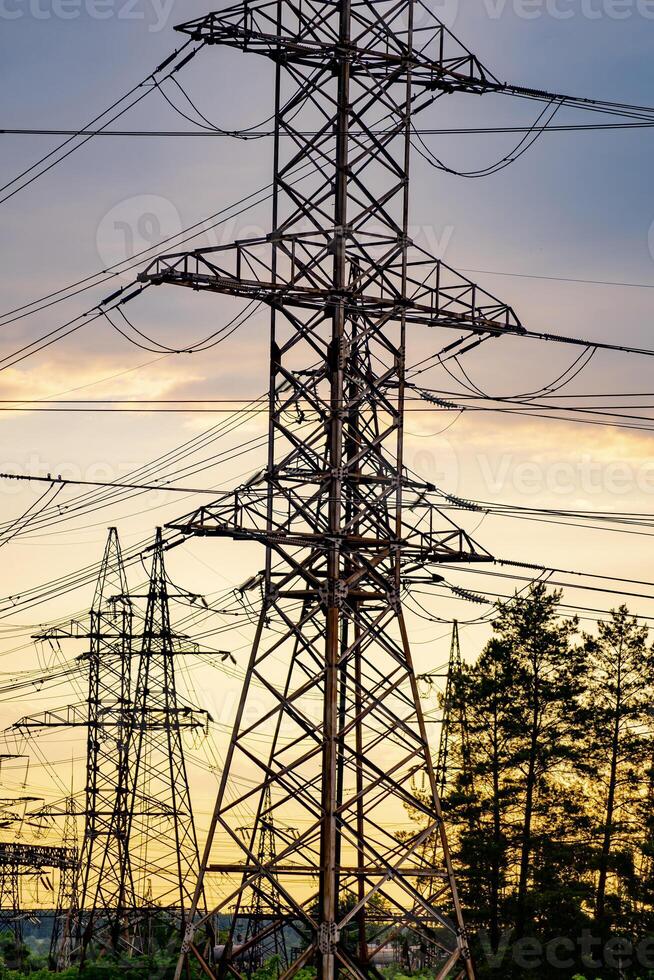 High voltage electric tower. Silhouette on sunset time. Power pylons on sunset time background. Selective focus photo