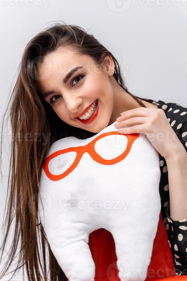 Girl holds soft toy in hands. Soft toy in shape of tooth in glasses. Oral care concept. photo