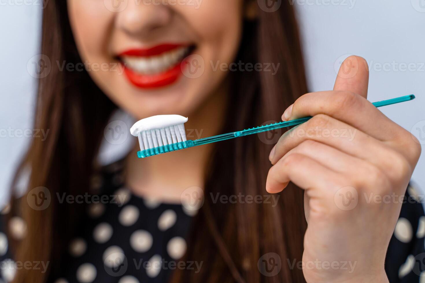 mujer con genial dientes participación cepillo de dientes en frente de cámara. borroso antecedentes. foto