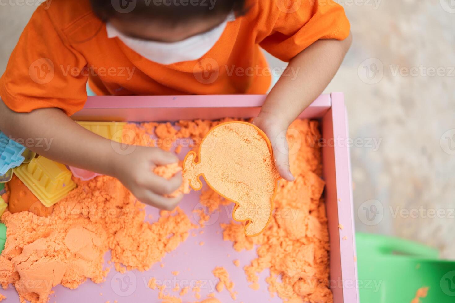 A child girl is playing with sand in a tray photo