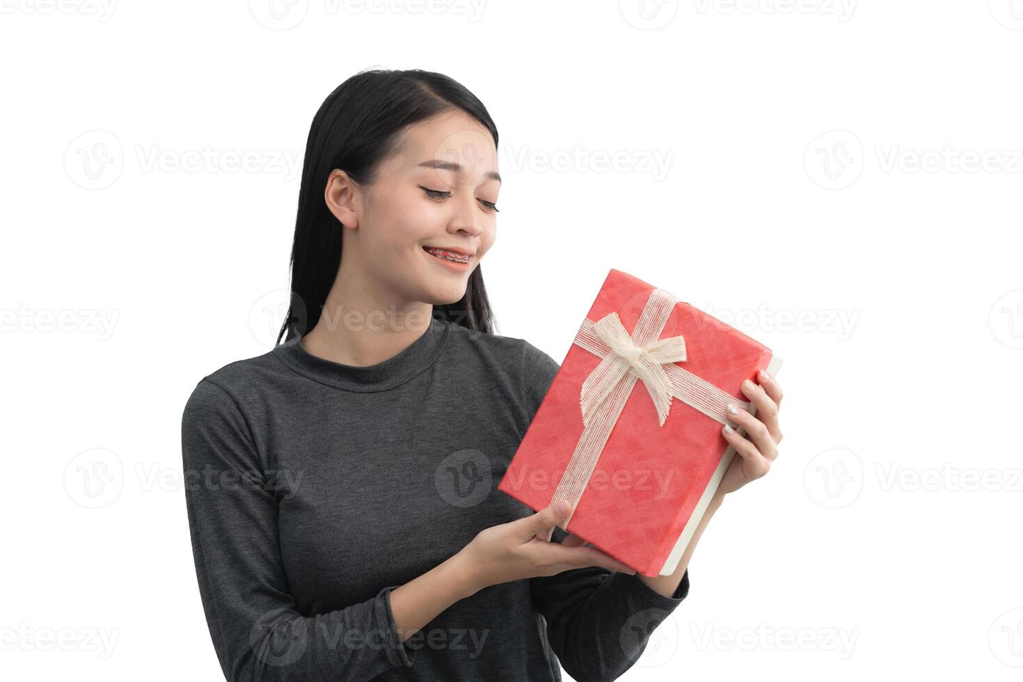 un mujer es participación un rojo presente con un blanco cinta. ella es sonriente y ella es contento. aislado en blanco antecedentes. foto