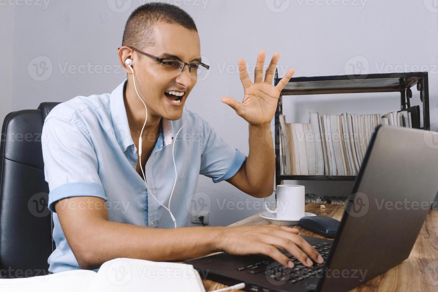 young latinx man using his computer. Hispanic male in a video chat. photo