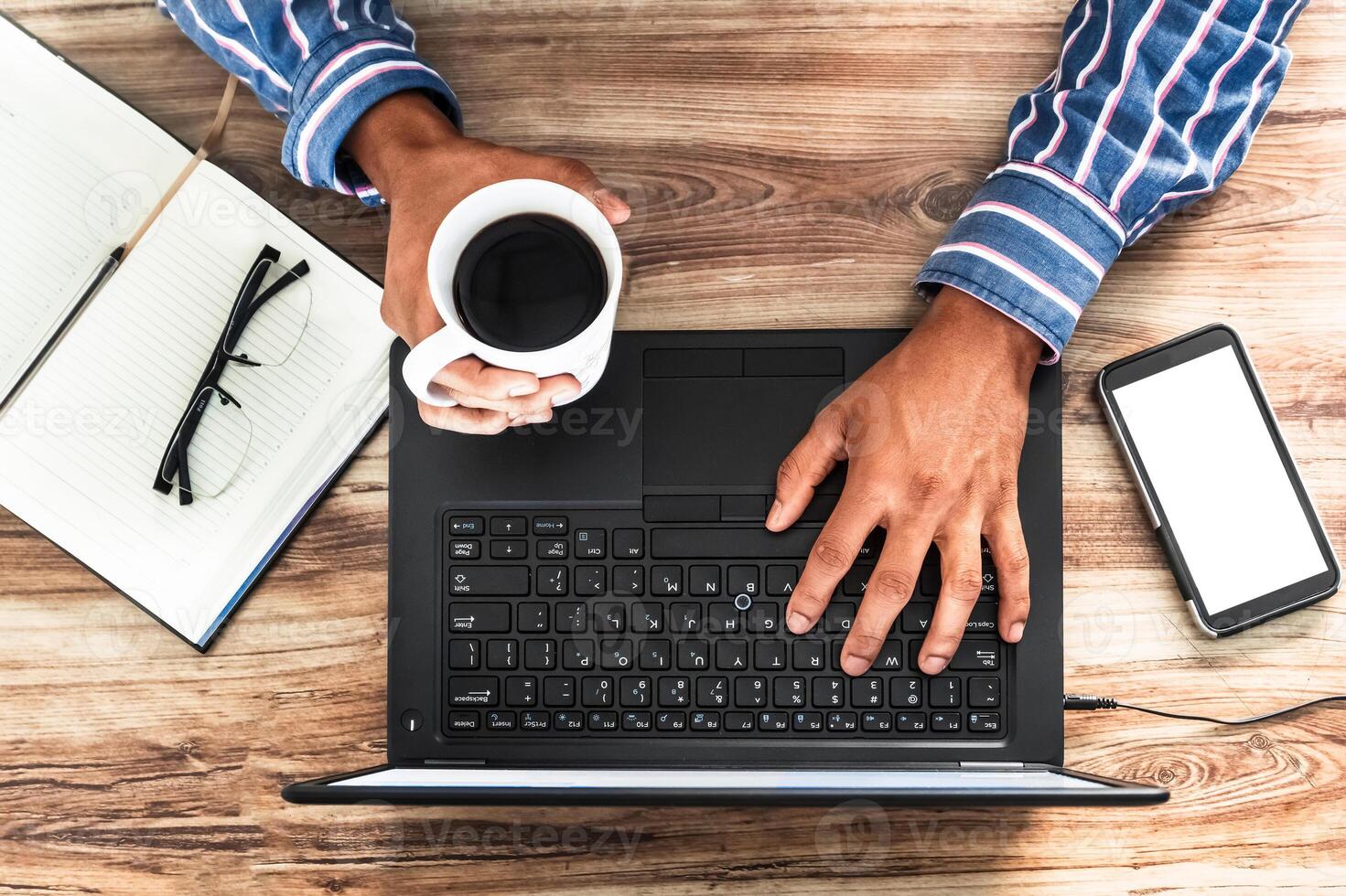 hands of a man holding a cup of coffee and typing on a laptop, office work concept. I work online. photo