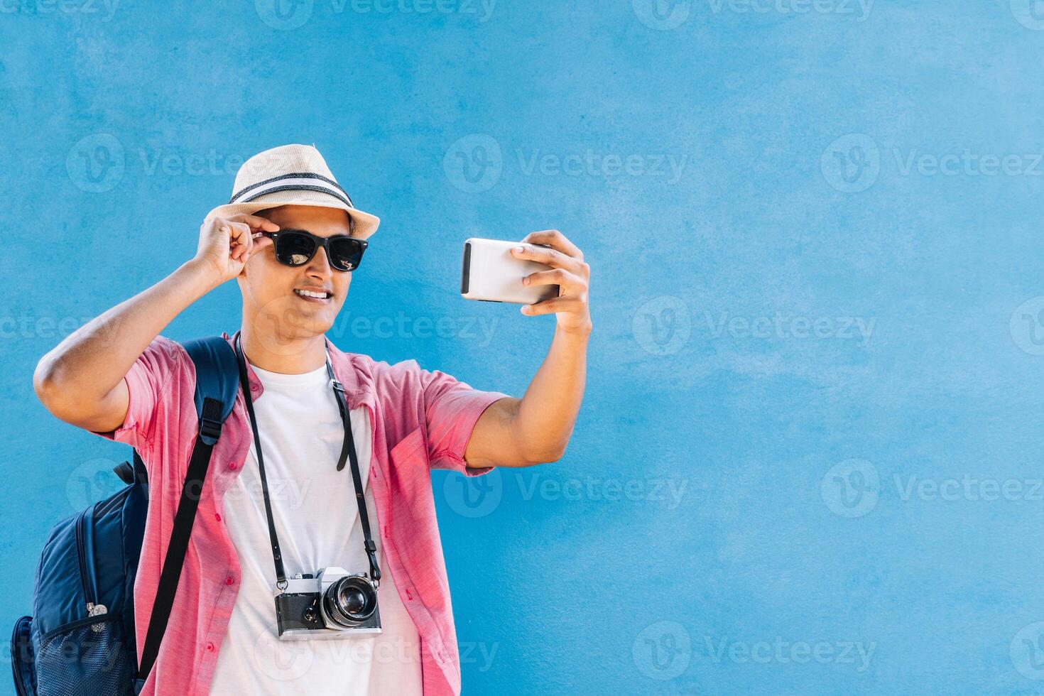 Latin American smiling wearing glasses and hat taking a selfie photo