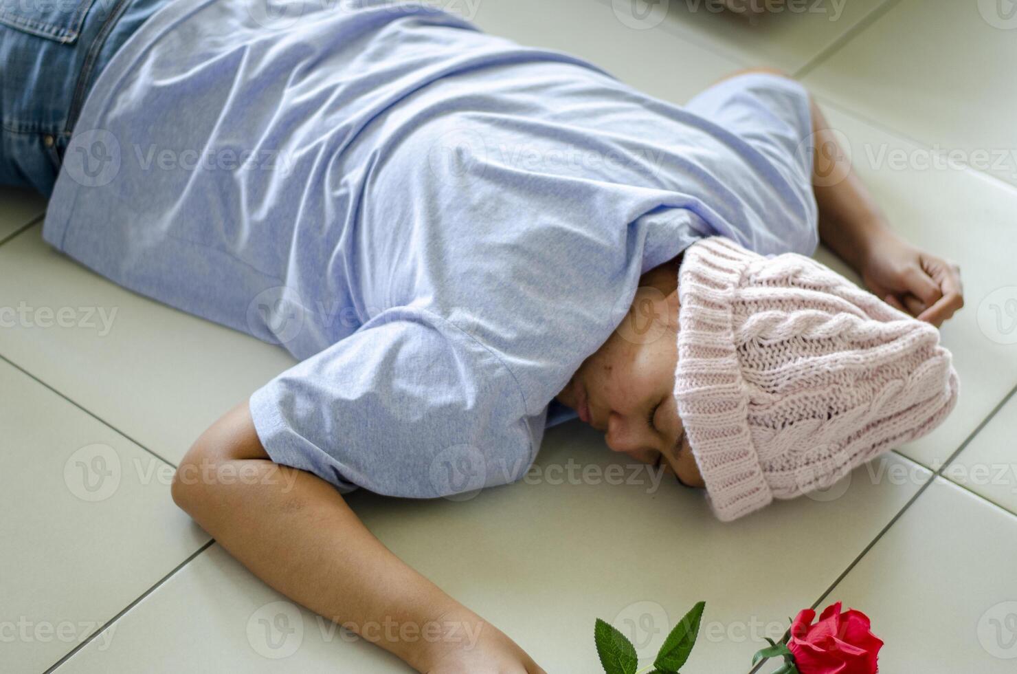 Asian woman with cancer, lying unconscious or fainting on the floor in the living room photo