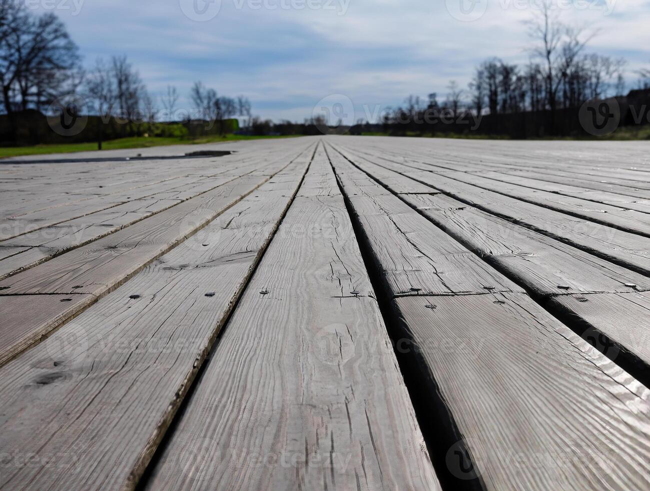 Boardwalk by the garden, wooden plank, decking, walkway, path or terrace, low angle view image of patio deck with blurred green background, copy space photo