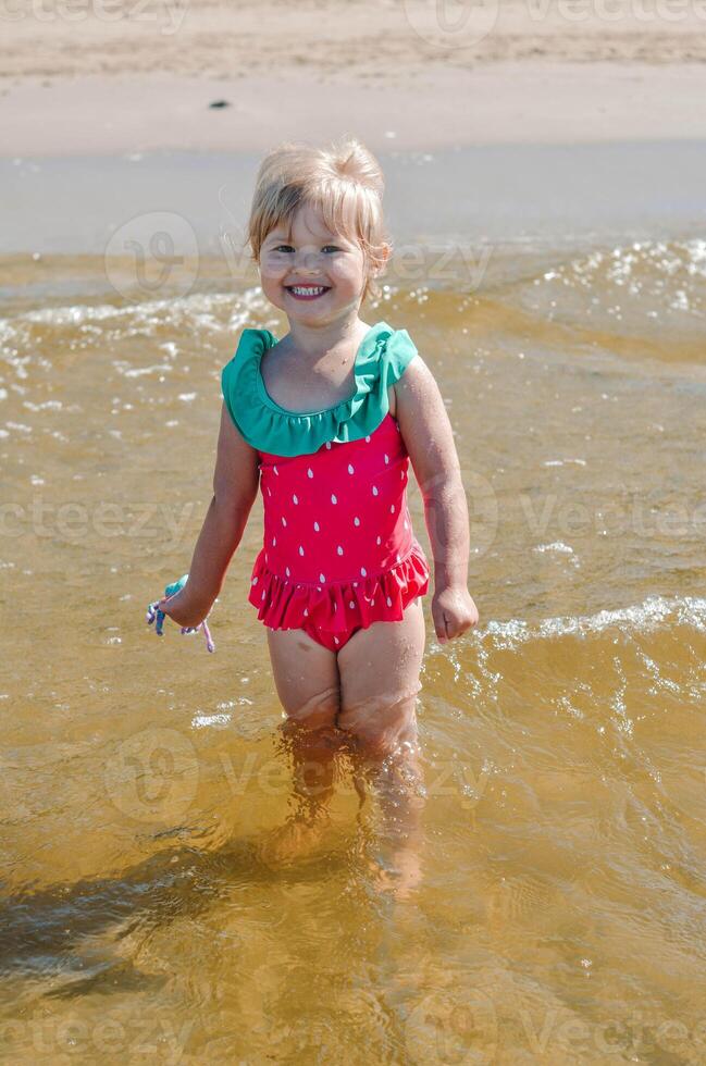 joven contento niño niña de europeo apariencia años de 4 4 teniendo divertido en agua en el playa ,tropical verano vocaciones,vacaciones.a niño disfruta el mar.vertical foto. foto