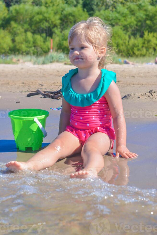 joven contento niño niña de europeo apariencia años de 4 4 teniendo divertido en el playa ,sonriente y mirando dentro el distancia,tropical verano vocaciones,vacaciones.a niño disfruta el mar.vertical foto