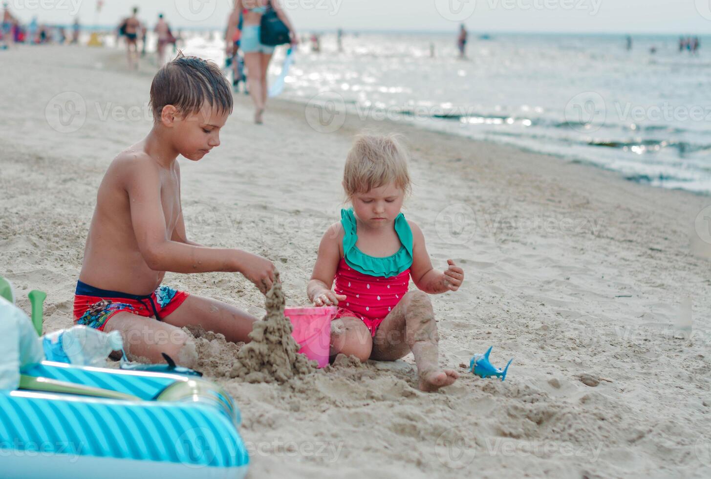 Brother and sister making sand castle on the beach in warm summer day.Family summer holidays concept. High quality photo