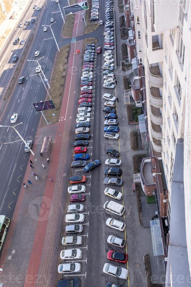 large parking lot for cars in front of a multi-storey residential building view from above photo