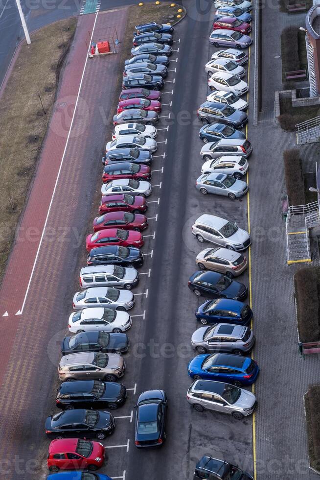 large parking lot for cars in front of a multi-storey residential building view from above photo