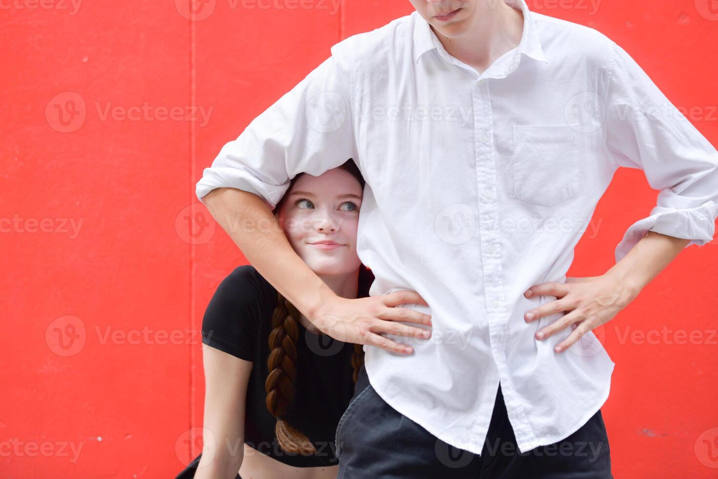 A couple is enjoying a summer vacation in the red wall background, happily showing their love to each other. photo