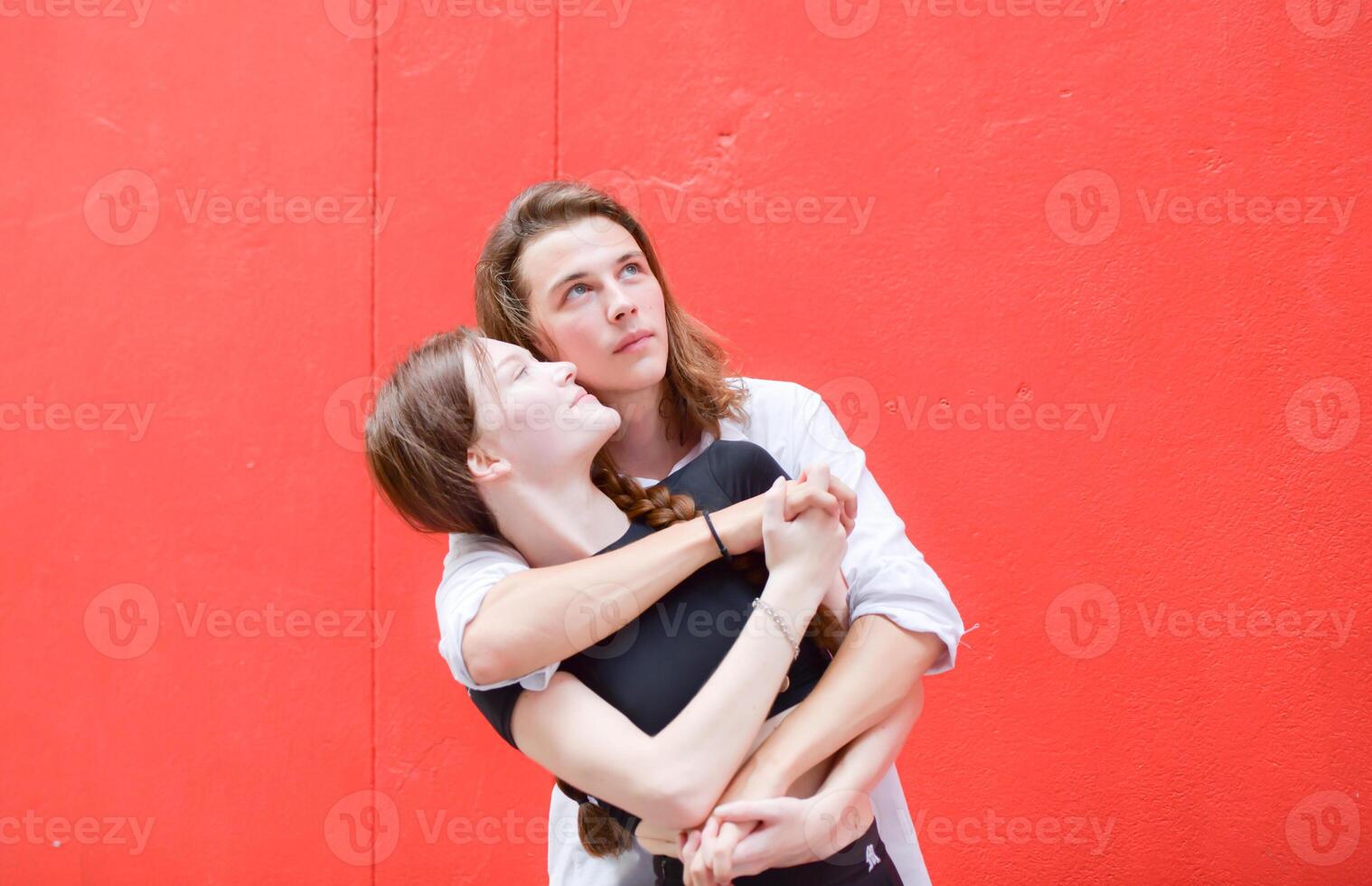 A couple is enjoying a summer vacation in the red wall background, happily showing their love to each other. photo