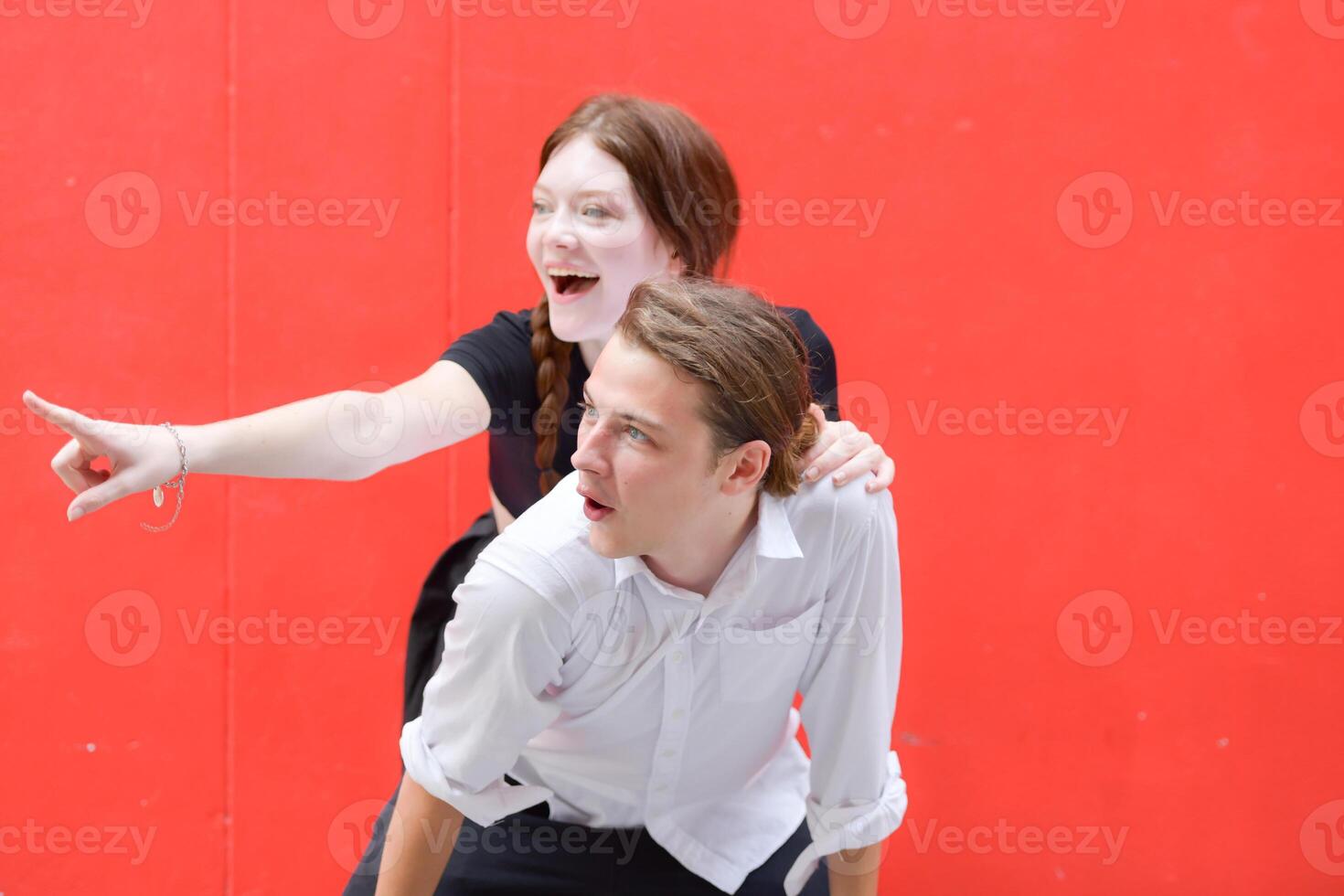 A couple is enjoying a summer vacation in the red wall background, happily showing their love to each other. photo