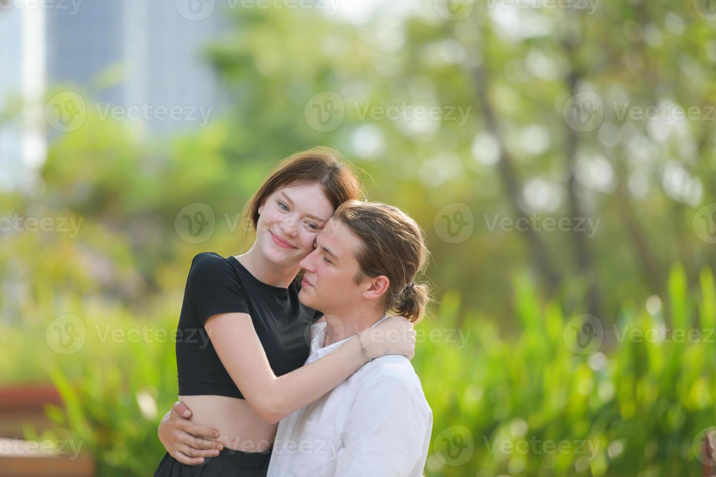 A couple is enjoying a summer vacation in the park, happily showing their love to each other. photo