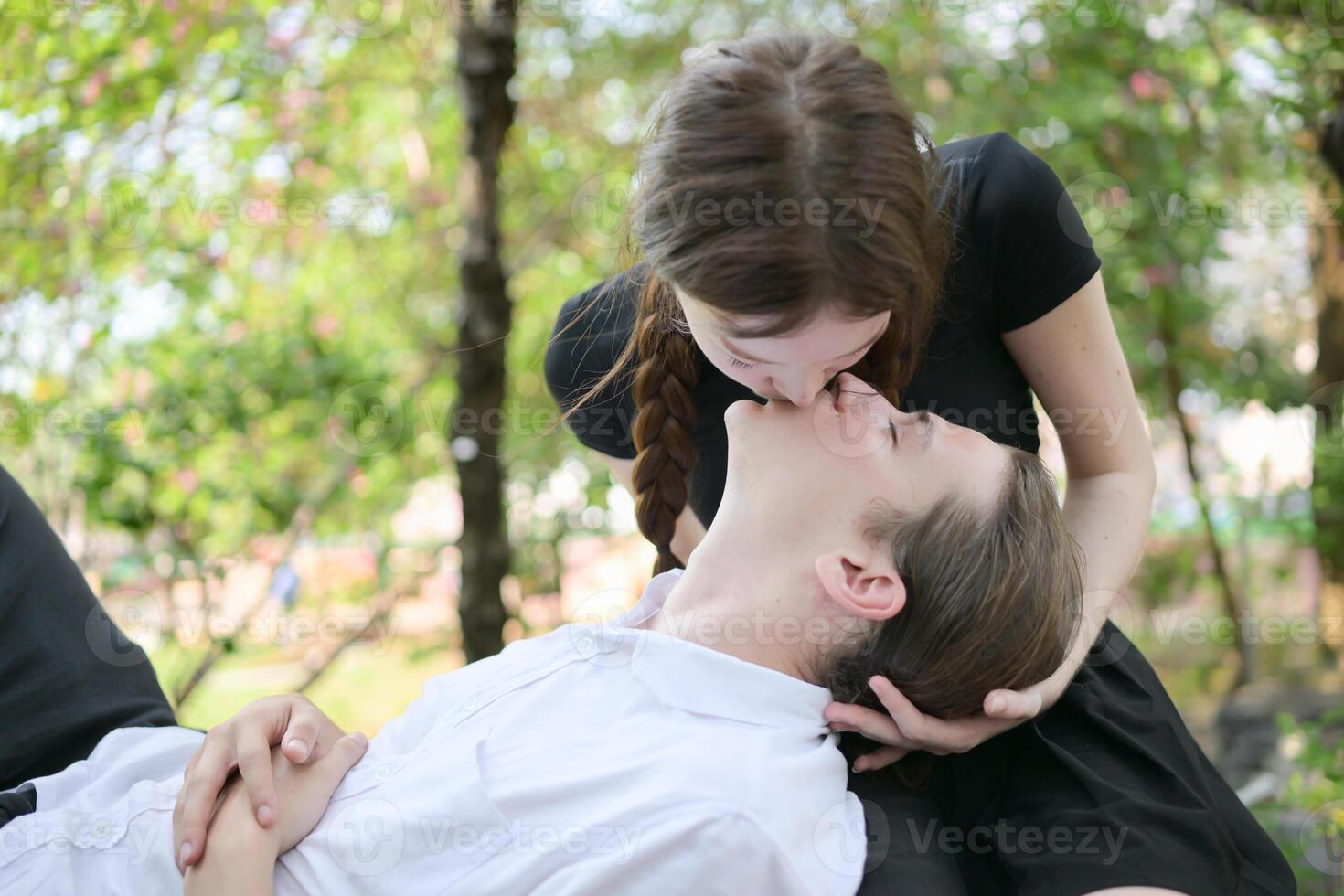 A couple is enjoying a summer vacation in the park, happily showing their love to each other. photo