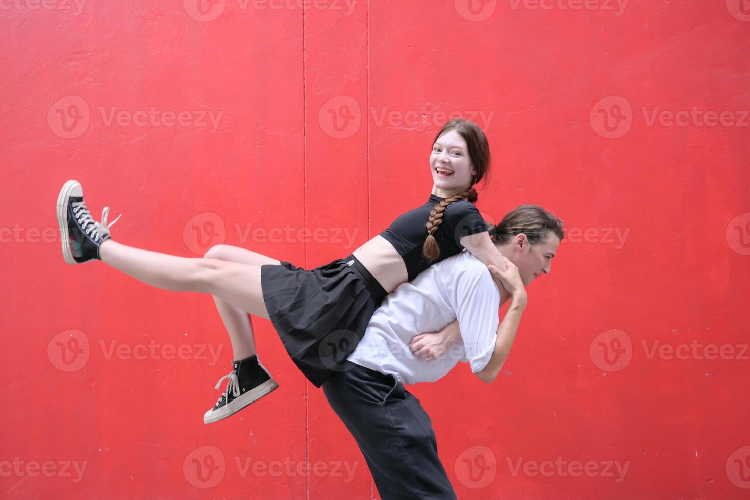 un Pareja es disfrutando un verano vacaciones en el rojo pared fondo, felizmente demostración su amor a cada otro. foto