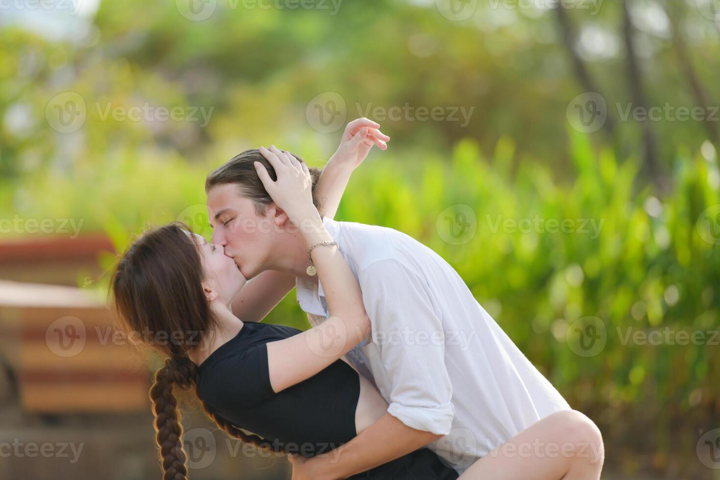 A couple is enjoying a summer vacation in the park, happily showing their love to each other. photo