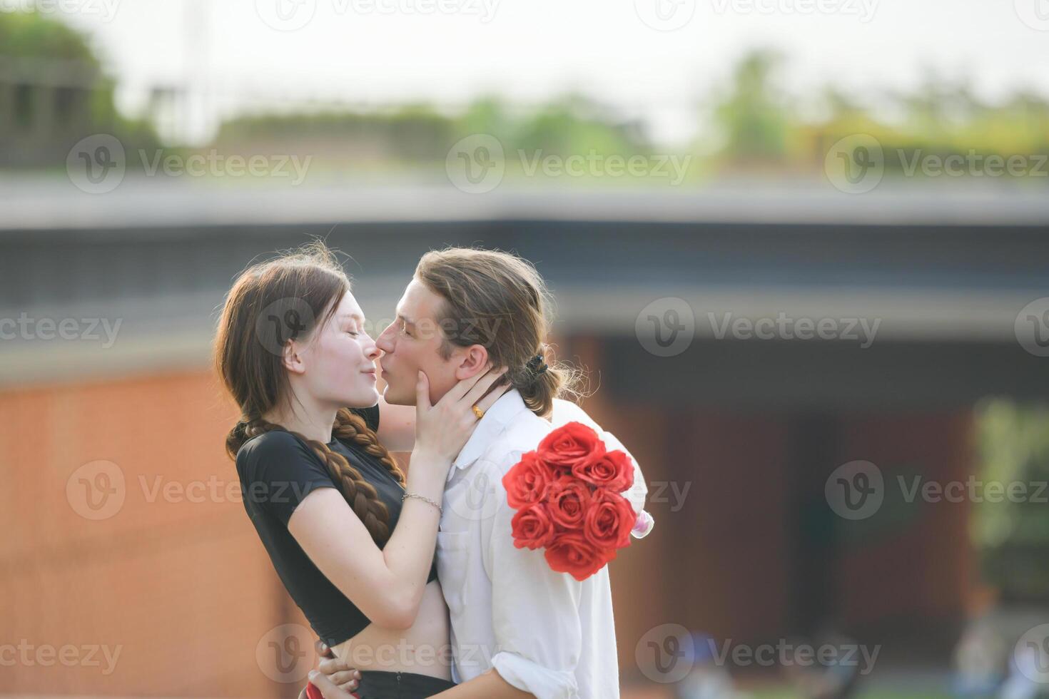 A couple is enjoying a summer vacation in the park, happily showing their love to each other. photo