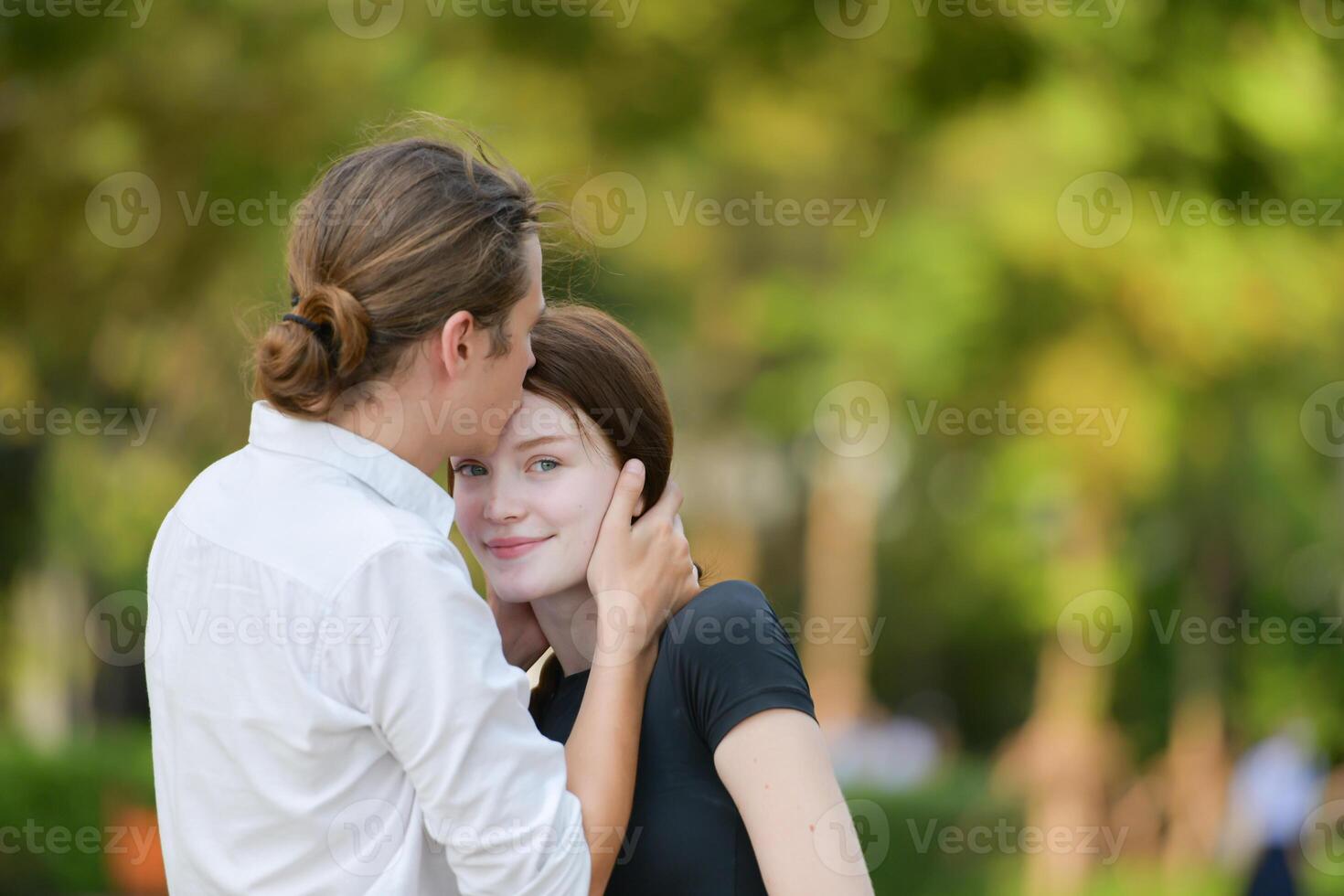 A couple is enjoying a summer vacation in the park, happily showing their love to each other. photo