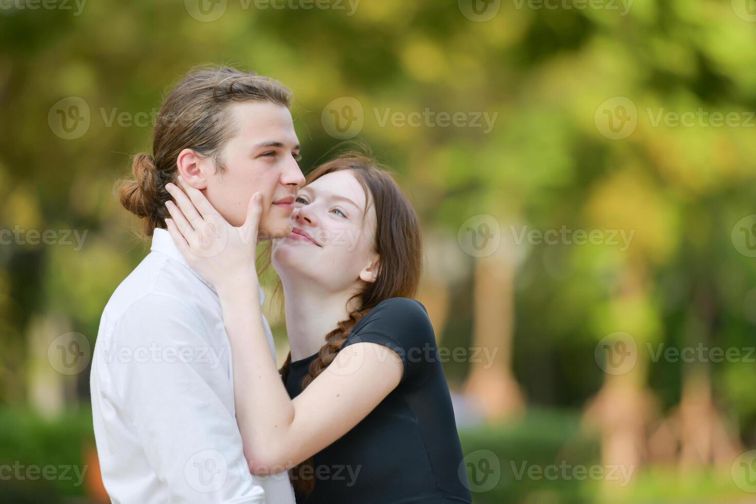 A couple is enjoying a summer vacation in the park, happily showing their love to each other. photo