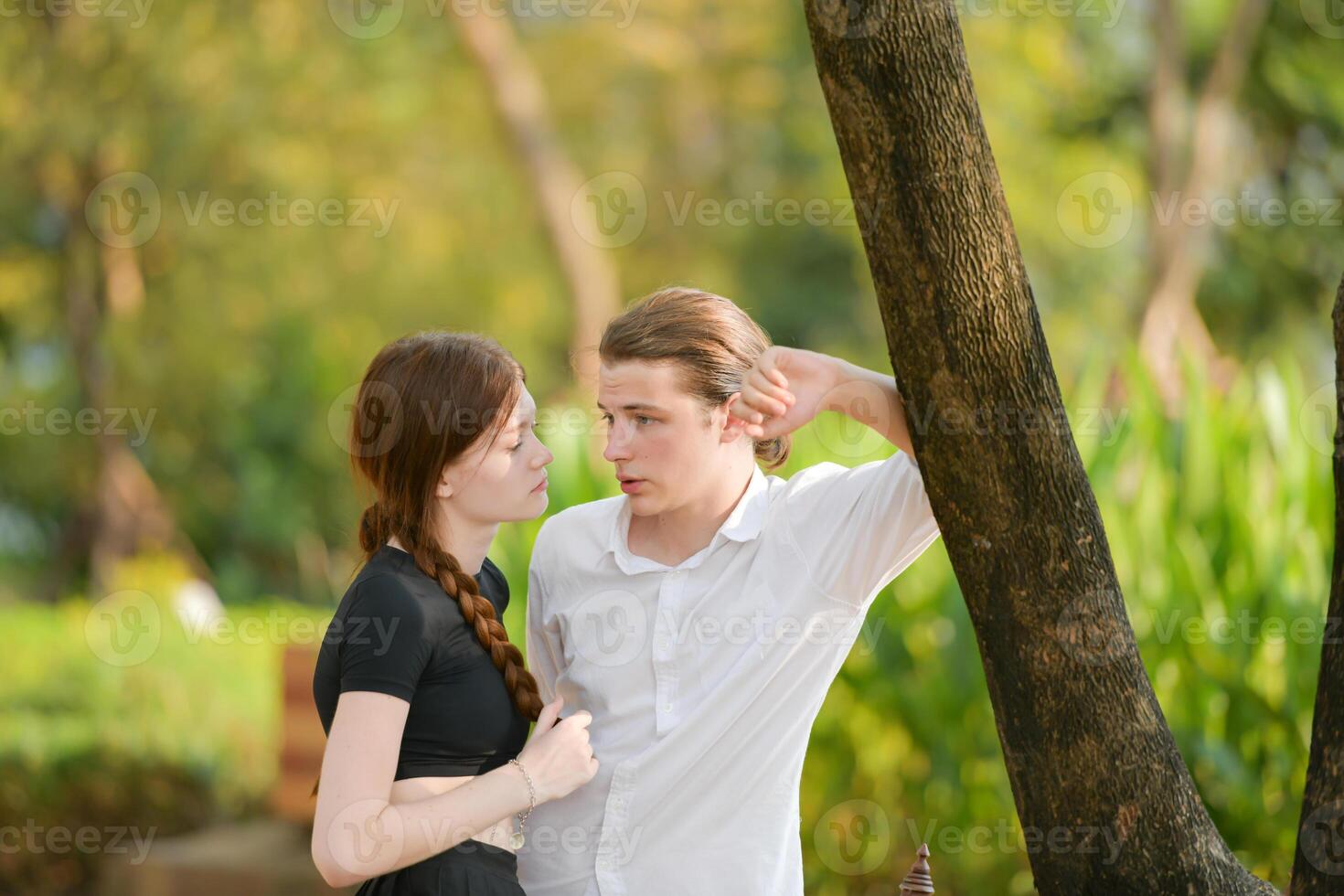 A couple is enjoying a summer vacation in the park, happily showing their love to each other. photo