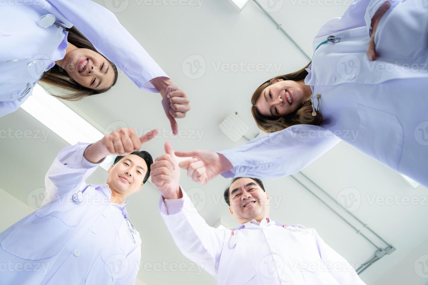 A delighted doctor team enjoying achievement in a hospital setting with thumbs up. photo