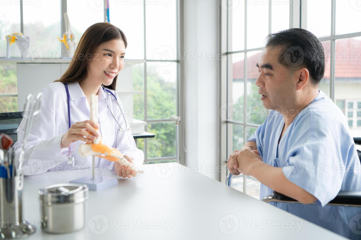 In the hospital office, A medical explains about the foot bones and their treatment to a patient photo