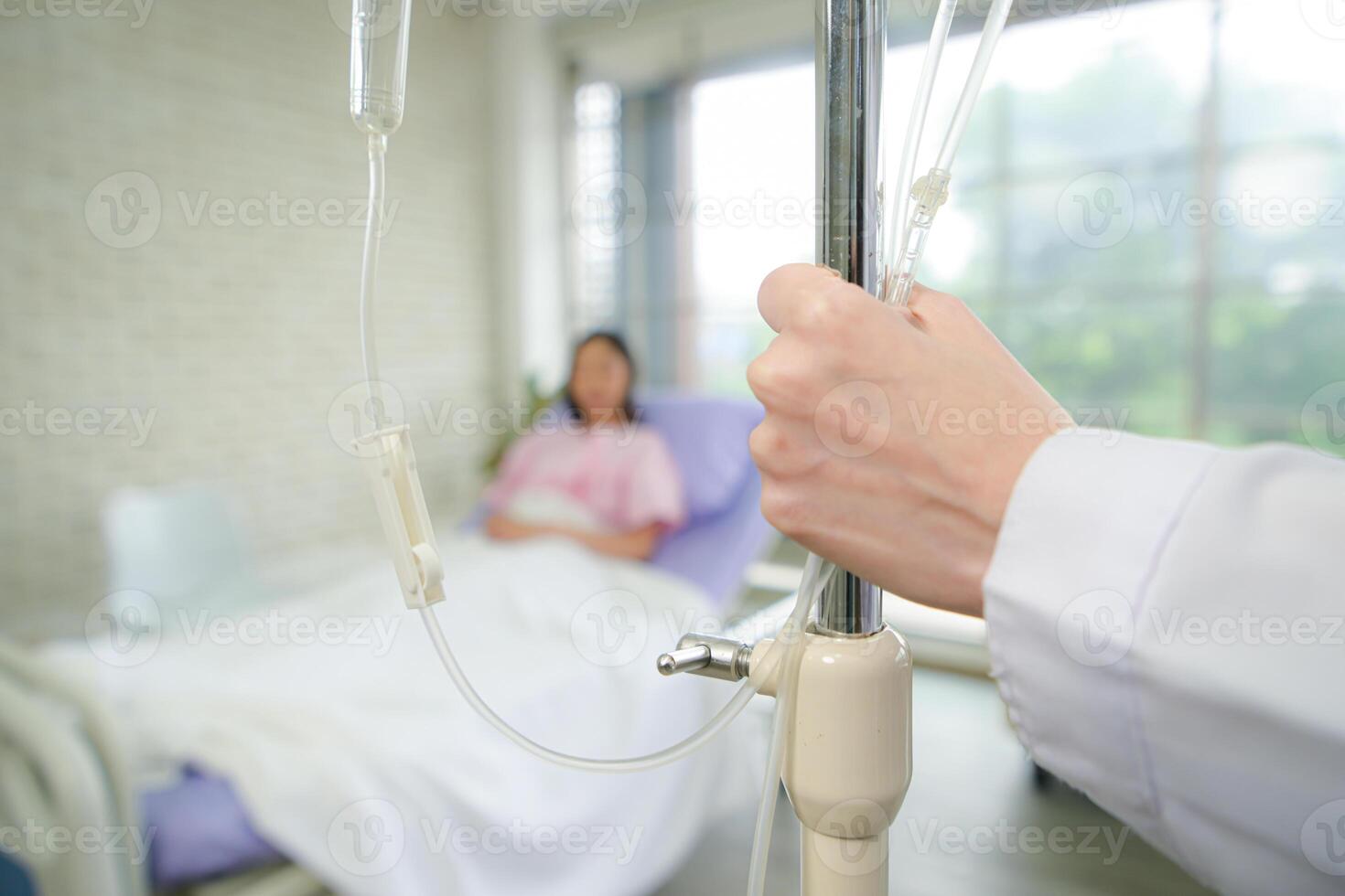 Female doctor with IV equipment will give IV fluids and examine patients lying in hospital beds photo