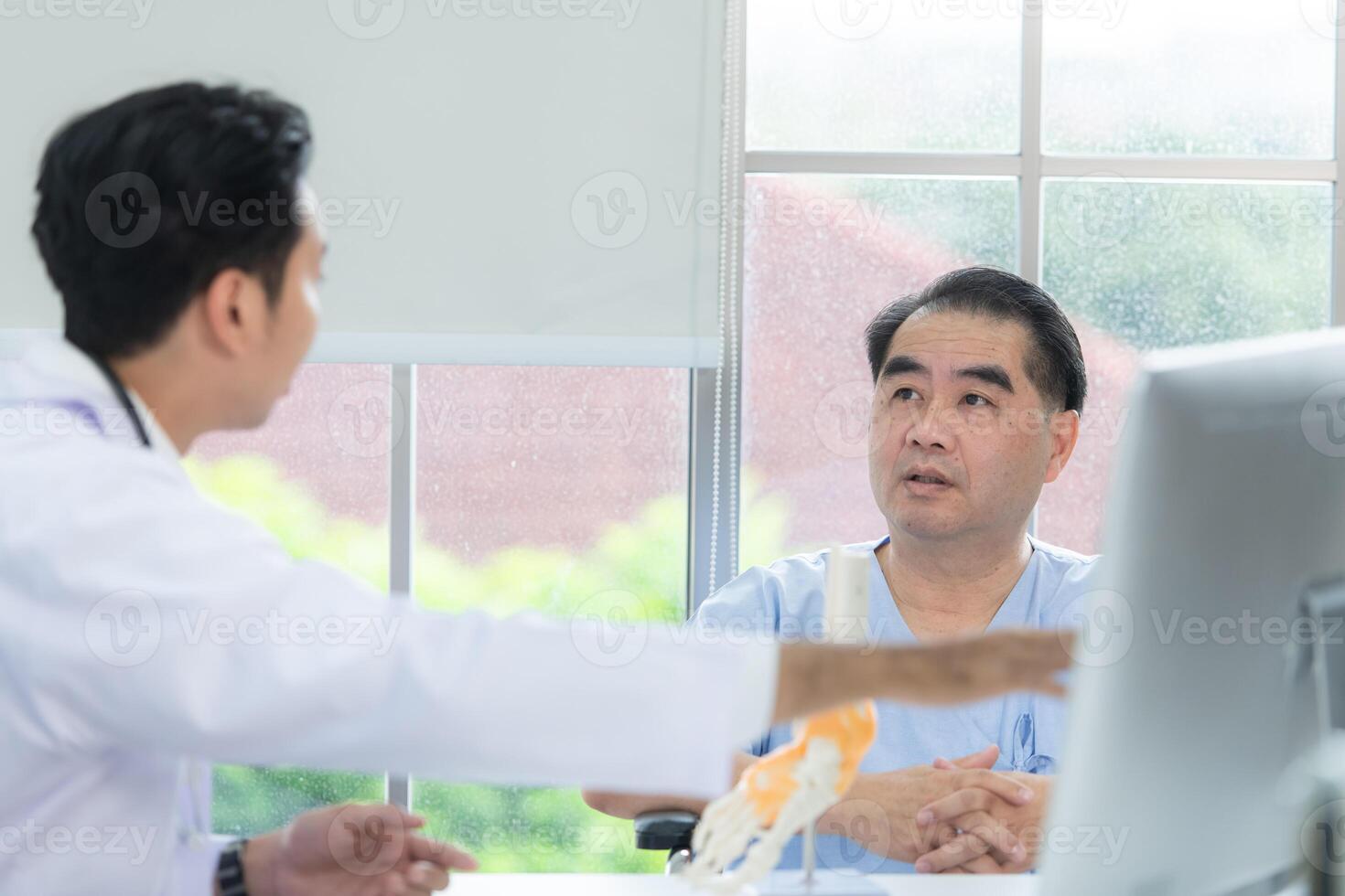 In the hospital office, A medical explains about the foot bones and their treatment to a patient photo