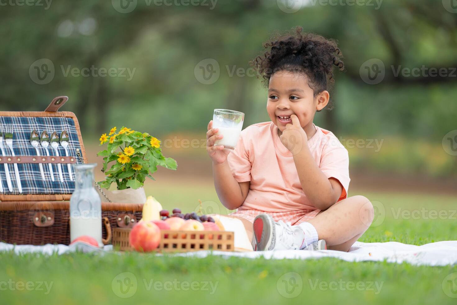 Happy family enjoying a picnic in the park, with kids drinking  milk, surrounded by nature photo