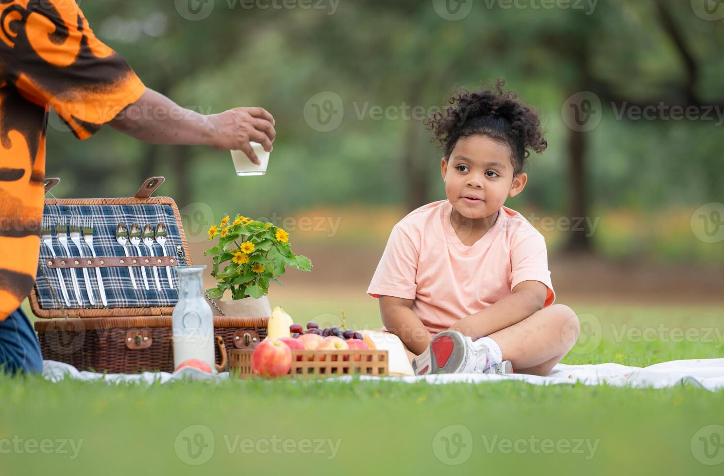 Happy family enjoying a picnic in the park, with kids drinking  milk, surrounded by nature photo
