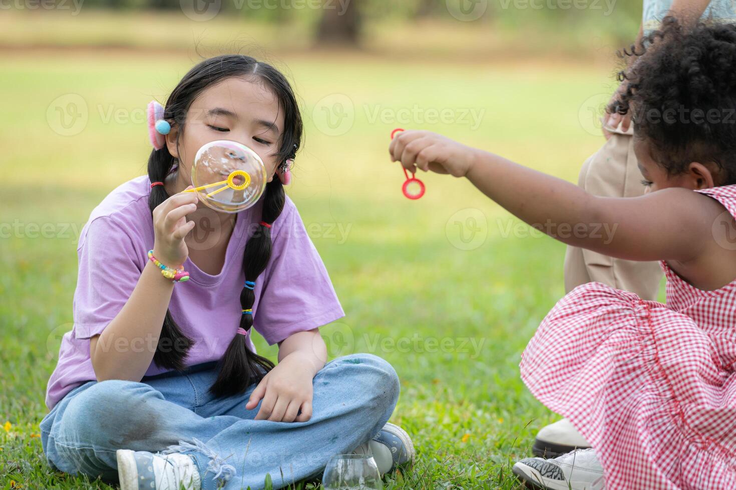 Children sitting in the park with blowing air bubble, Surrounded by greenery and nature photo