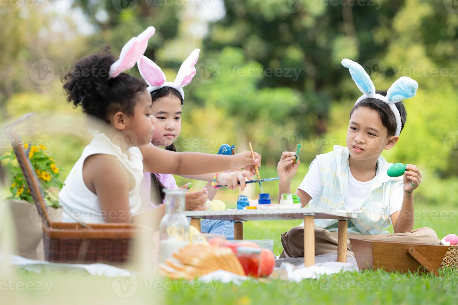 contento familia disfrutando un picnic en el parque, niños sentado y colorante su hermosa Pascua de Resurrección huevos. foto