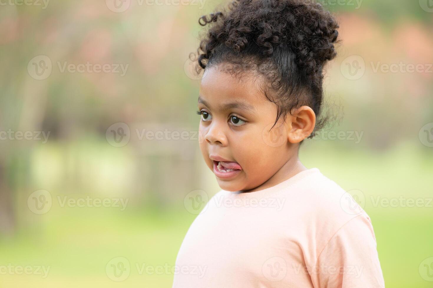 Happy young girl smiling in a green park during summer, portraying childhood joy and innocence photo