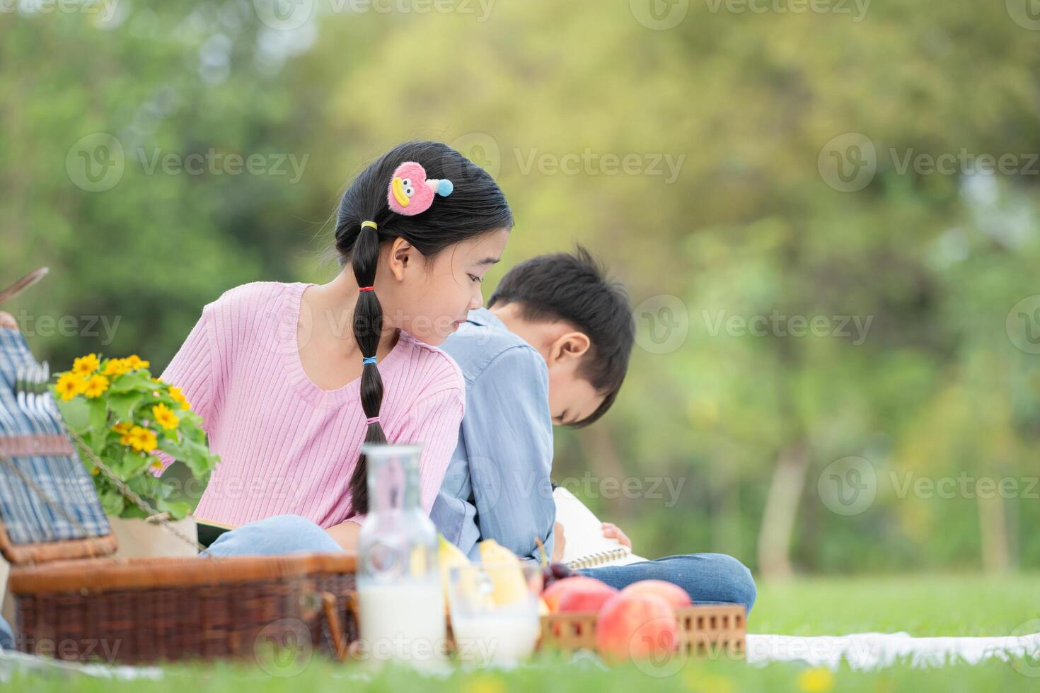 Happy family enjoying a picnic in the park, Children sitting back to back and reading books. photo