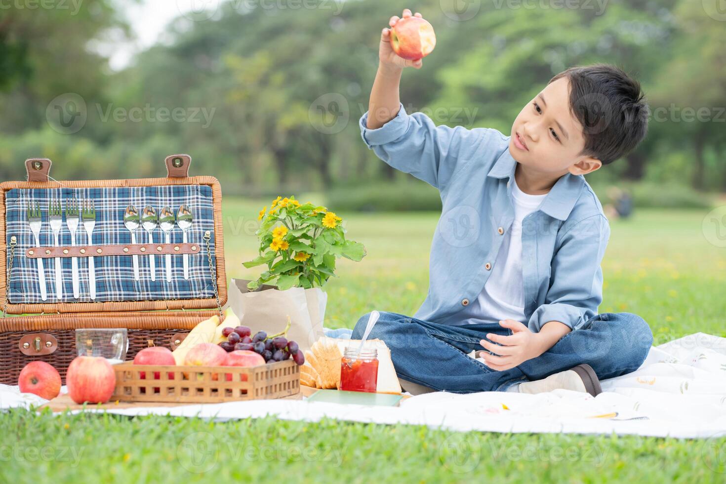 Happy family enjoying a picnic in the park, with children having fun sitting, surrounded by nature photo