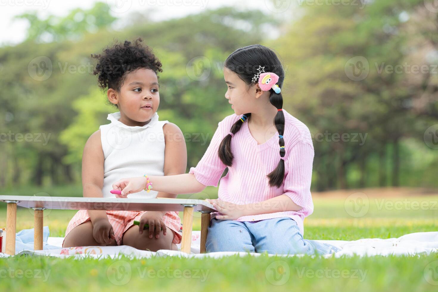 contento familia disfrutando un picnic en el parque, niños son teniendo divertido dibujo en papel metido en el mesa. foto