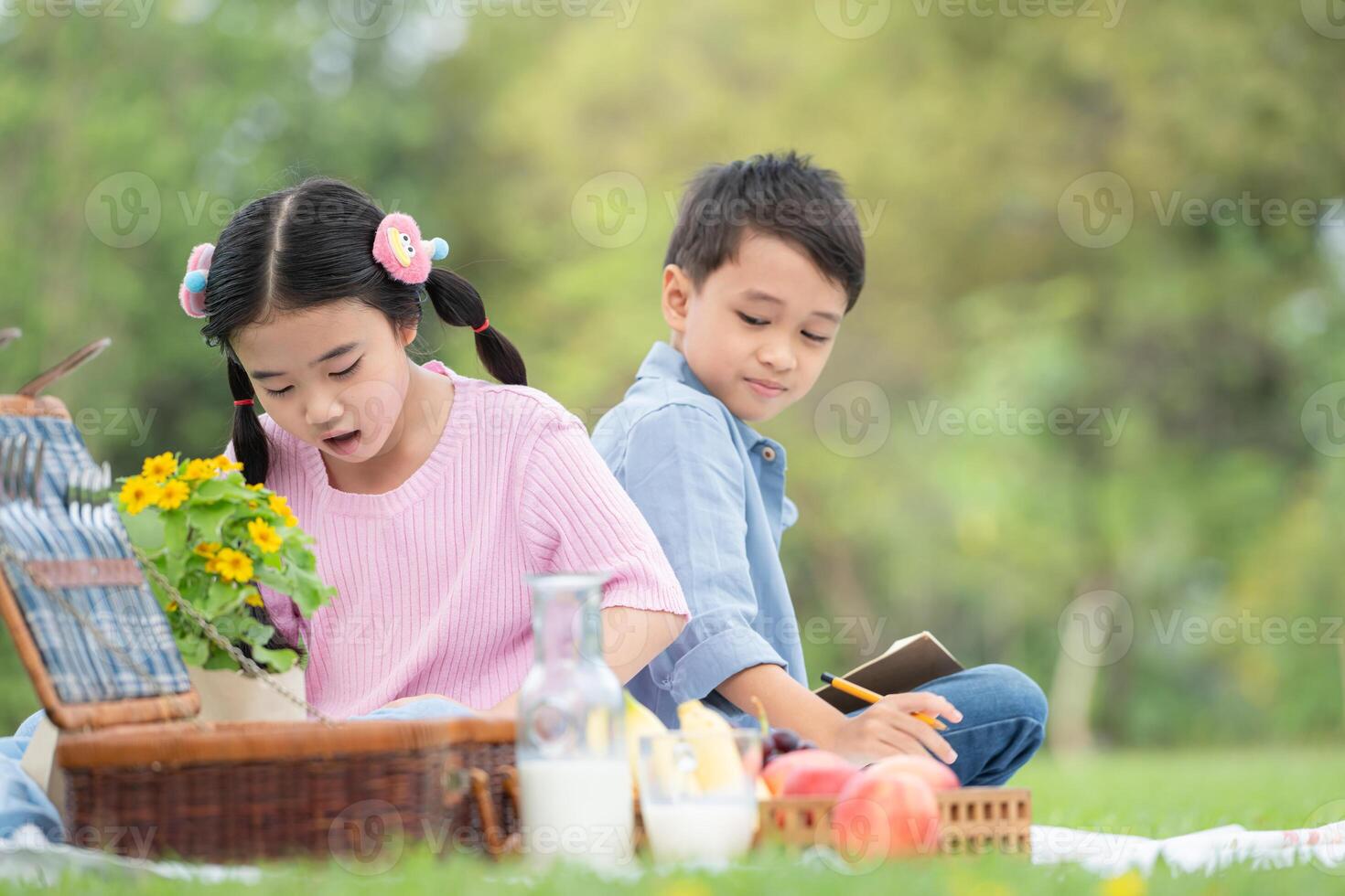 Happy family enjoying a picnic in the park, Children sitting back to back and reading books. photo