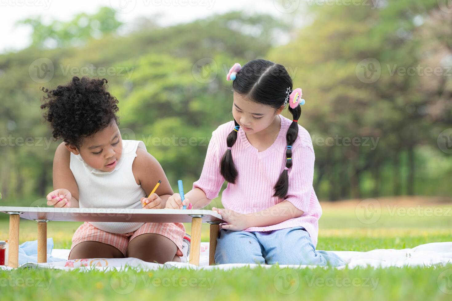 Happy family enjoying a picnic in the park, Children are having fun drawing on paper placed on the table. photo