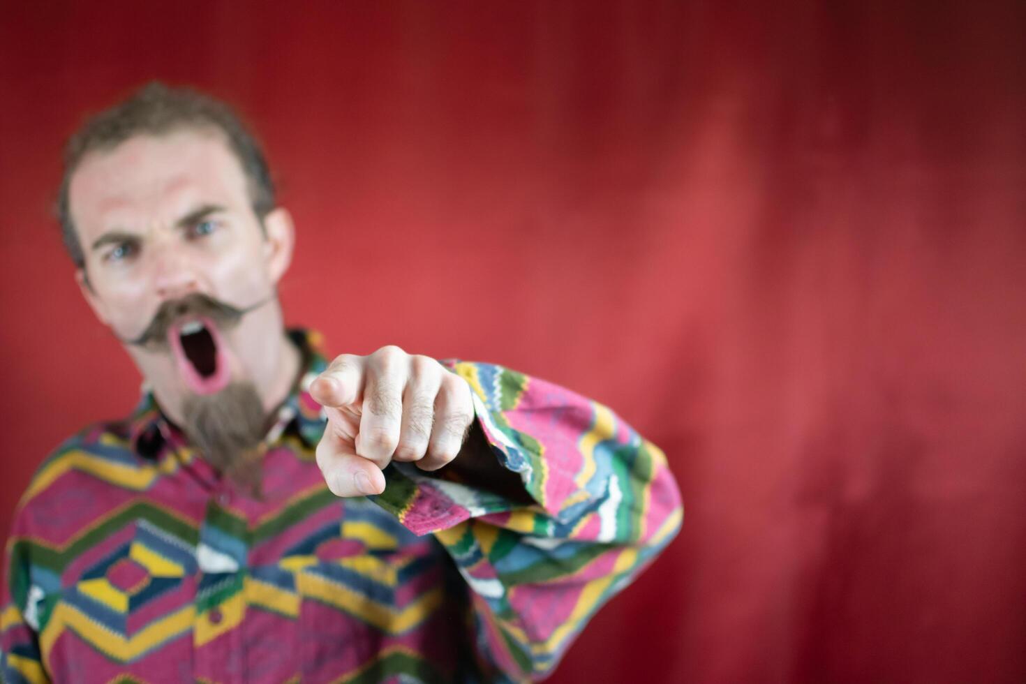 Angry hipster man pointing at camera shouting and with furious expression photo