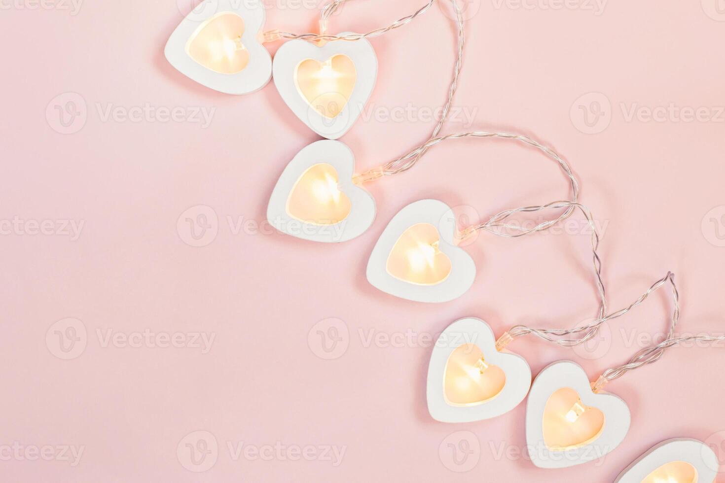 Heart shape garland on pink pastel background. Valentine's Day or wedding party decoration. Love concept photo