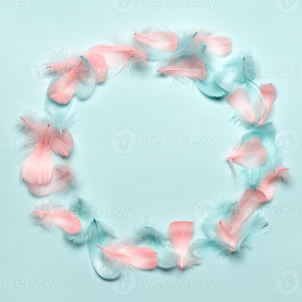 Happy easter greeting card template. Round frame made of colorful feathers on pastel blue background. Flat lay, copy space photo