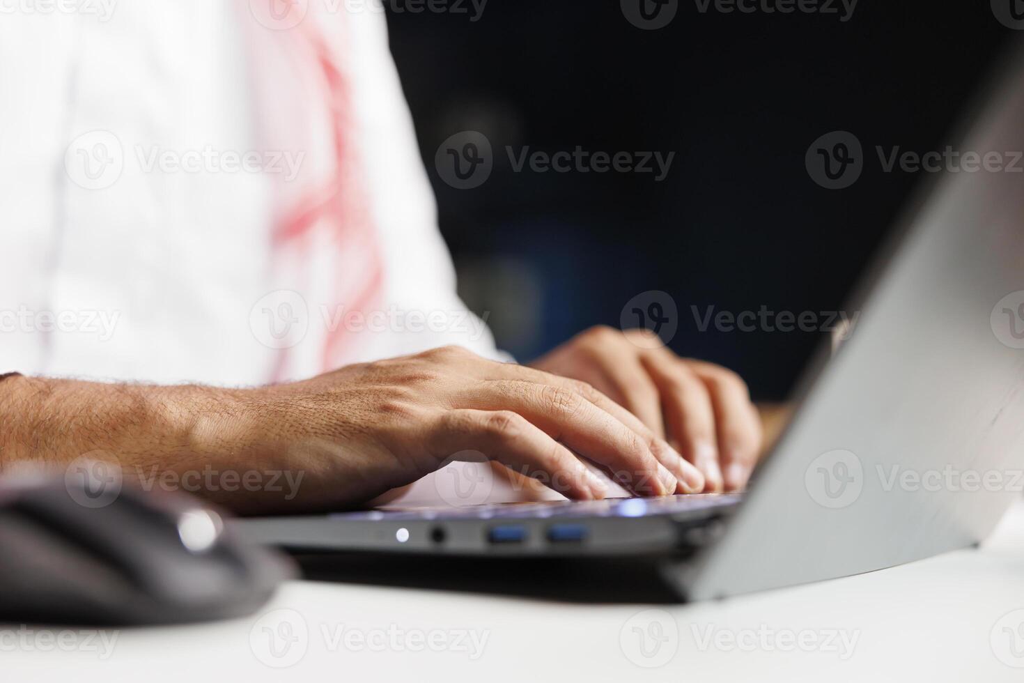 Selective focus on hands of a Middle Eastern person typing, taking notes on a minicomputer while staying connected wirelessly. Close-up shot of a person utilizing a modern digital laptop. photo
