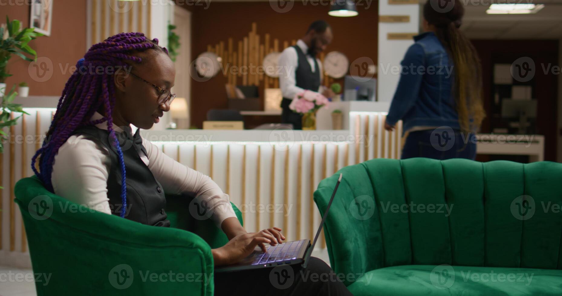 Staff member working on laptop in reception lobby, writing guest information on list to book room reservations. Woman concierge worker ensuring easy check in at luxurious hotel. photo