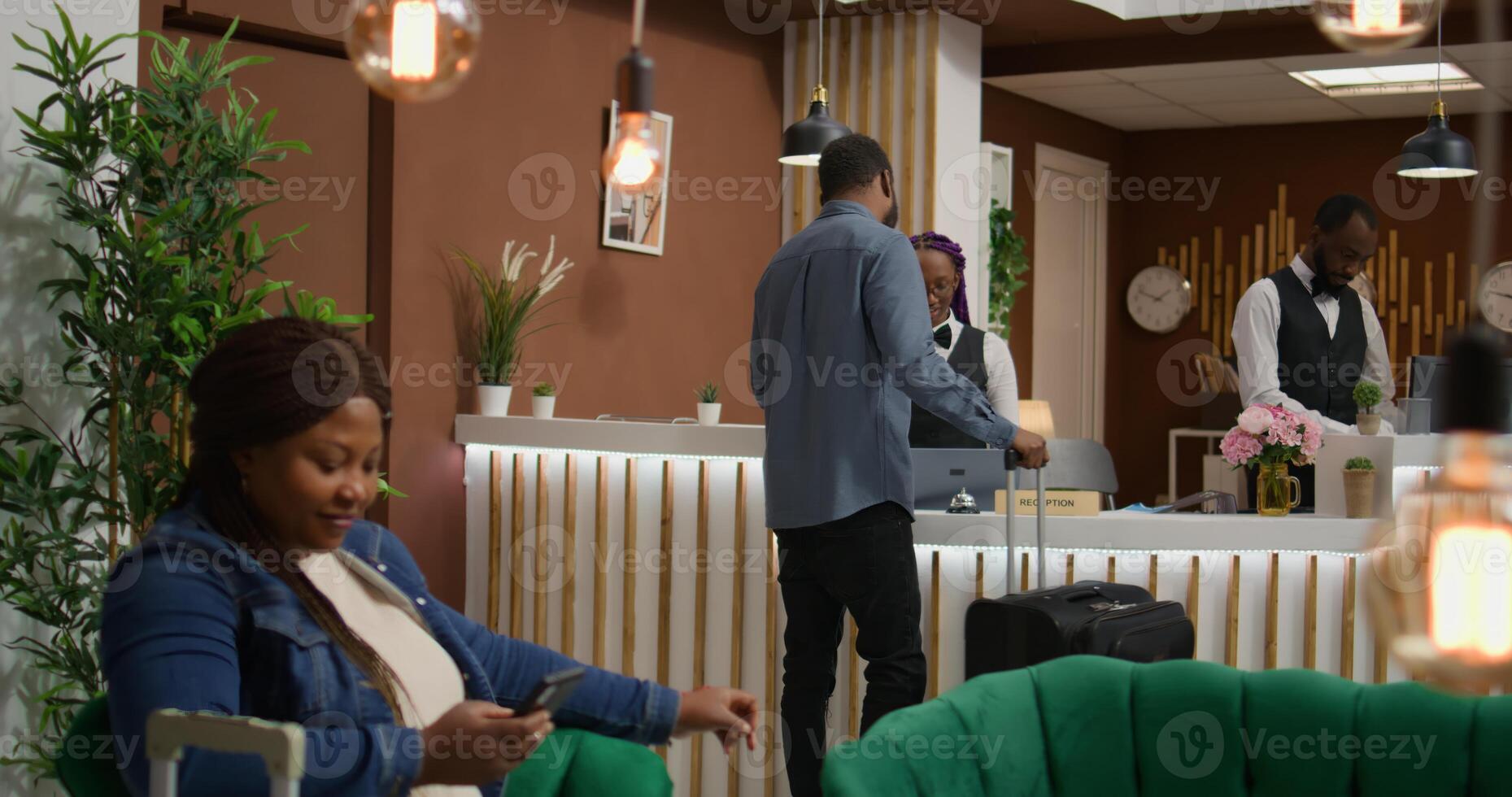 Guest travelling with luggage at hotel, receiving access key card at reception after long flight. African american man on vacation at five star holiday resort, preparing to see accommodation. photo